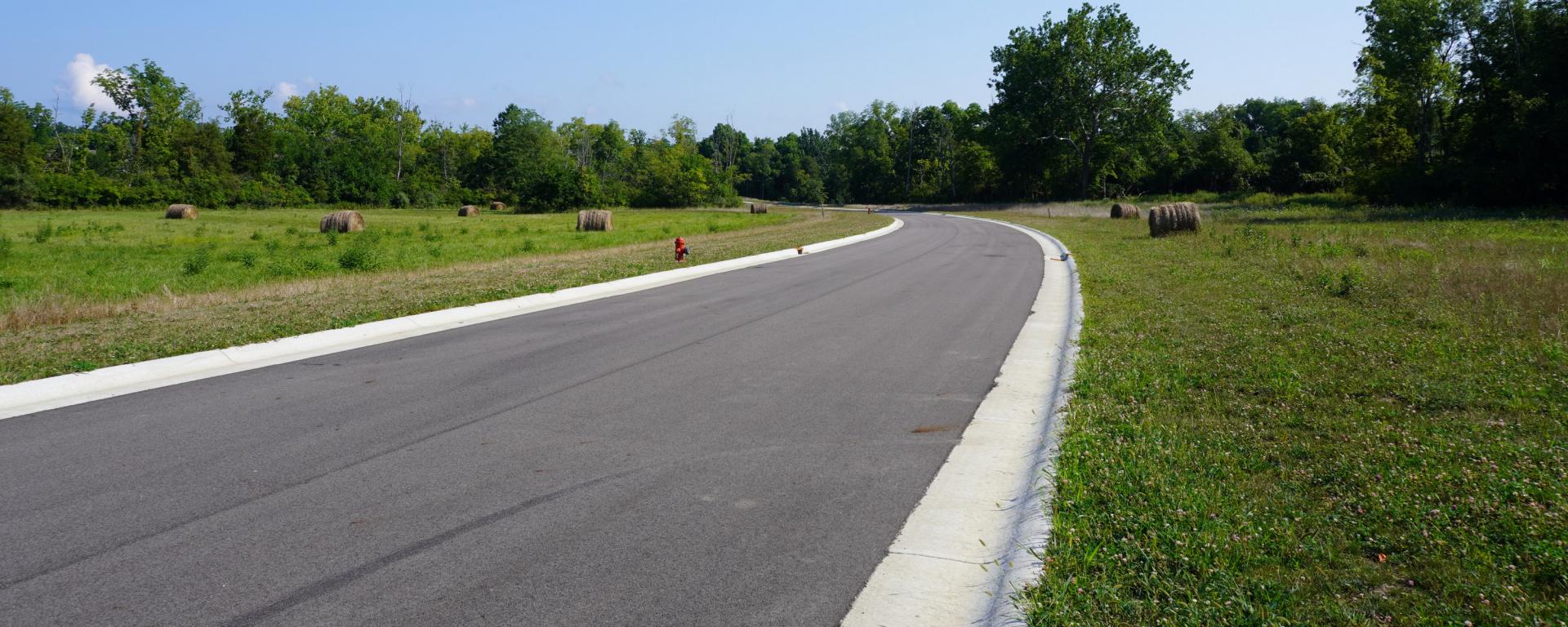 newly paved roadway surrounded by hay bales