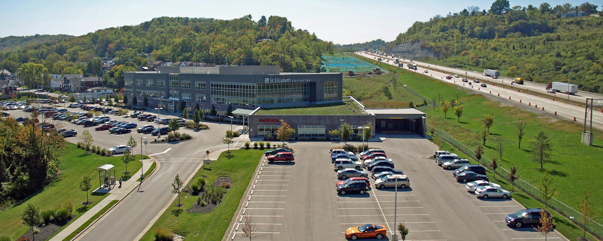 aerial of facility and parking lot, featuring highway in the back