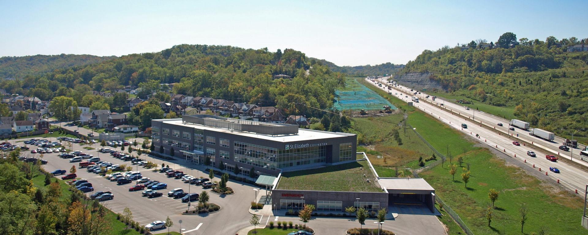 aerial of facility and parking lot, featuring highway in the back