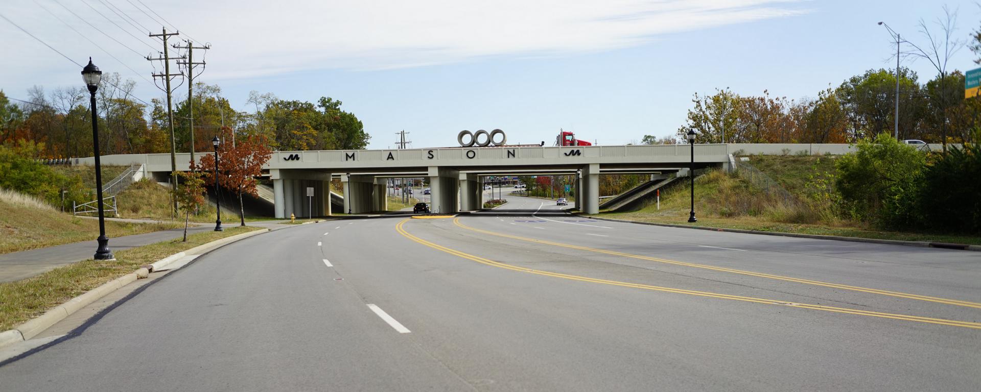 photo of empty roadway with bridge over it and lamp post