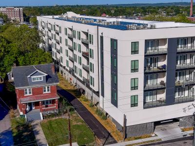 aerial photo of white apartment building with small red house next to it